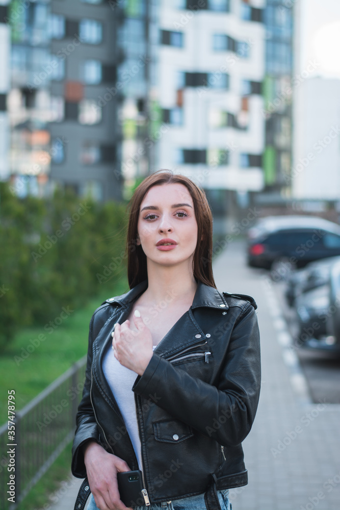 beautiful stylish young girl in a black leather jacket on the streets