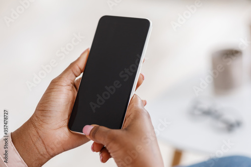 Mockup of smartphone with black screen in hands of unrecognizable black woman