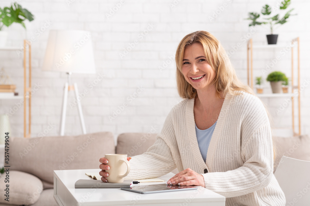 Business woman works from home. Female with cup, notepad and tablet Business woman works from home. Female with cup, notepad and tablet