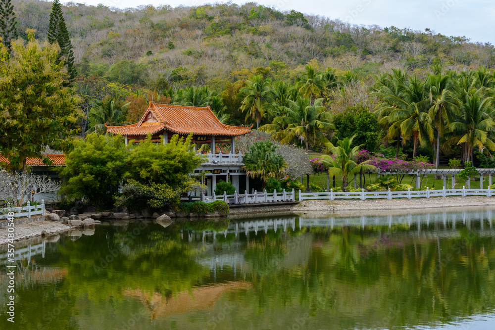 Green lake surrounded by gazebos, temples, mountains, flowers, palm grove and stone fence on the territory of Buddhist center Nanshan. Green lake surrounded by gazebos, temples, mountains, flowers, palm grove and stone fence on the territory of Buddhist center Nanshan.