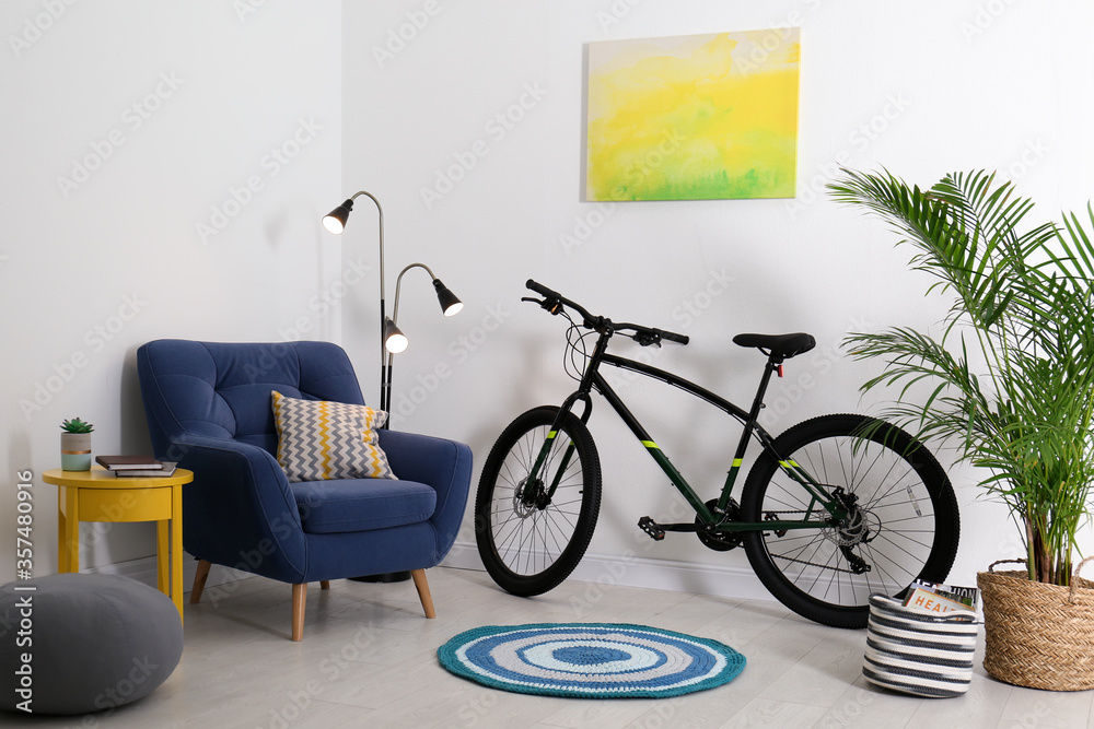 Modern bicycle and comfortable armchair in stylish living room interior Modern bicycle and comfortable armchair in stylish living room interior