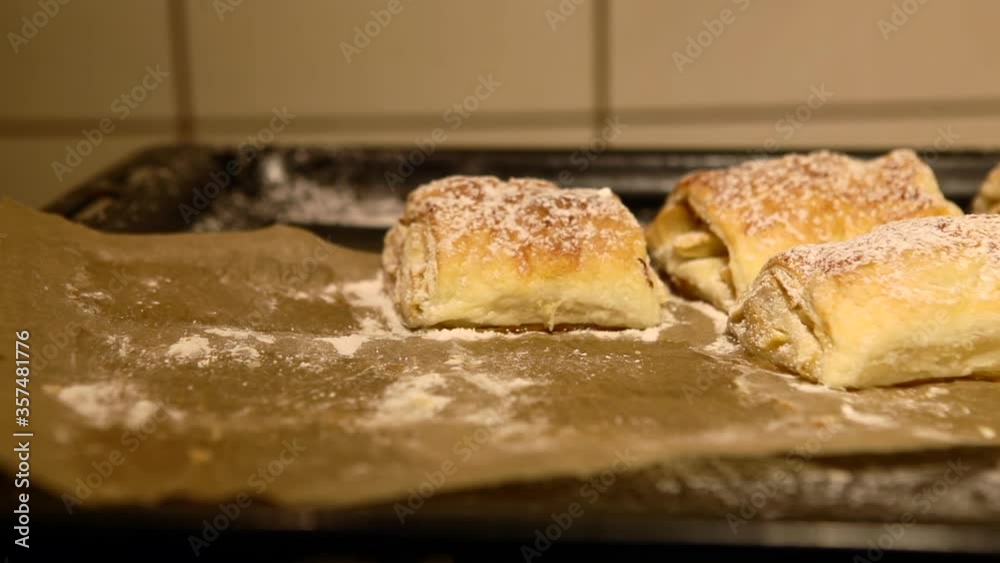 Freshly baked buns with apples in the oven. The chef sprinkles icing sugar on fresh frozen food in the kitchen. Freshly baked buns with apples in the oven. The chef sprinkles icing sugar on fresh frozen food in the kitchen.