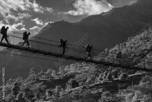 A group of trekkers crossing the suspension bridge ove Marshyangdi river and their way to Bhulbhule village and Besi Sahar village, Nepal, Nepal Himalayas