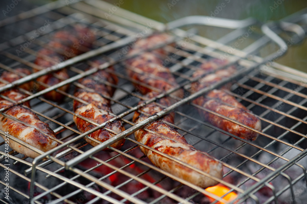 Hot sausage grilling outdoors on a barbecue grill.