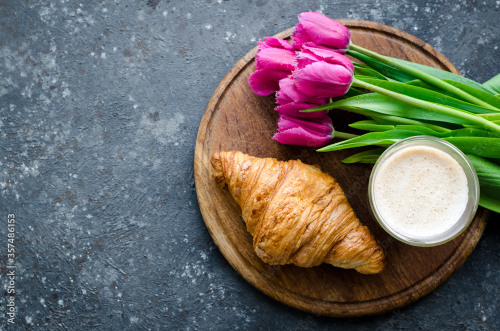 Cup of coffee with bouquet of pink tulips and croissant Cup of coffee with bouquet of pink tulips and croissant