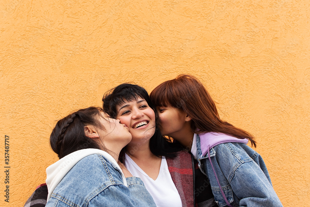 Happy mom with two daughters on an orange background