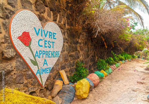 Colorful street of african village on NGor island with black lava stone masonry walls composed of various-shaped rocks and exotic plants photo