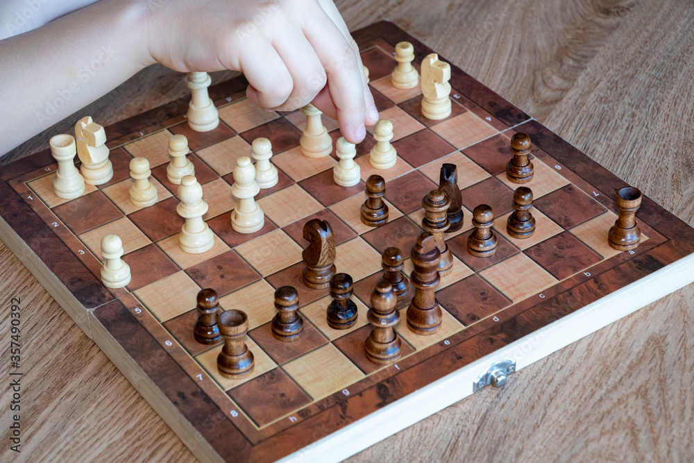 A child's hand moves a chess piece. Educational Intelligent Games