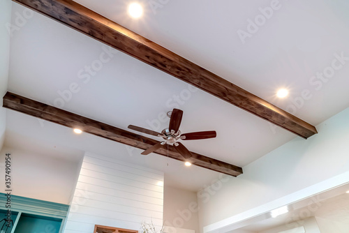 Wood beams and recessed bulbs with ceiling fan and lights at the center
