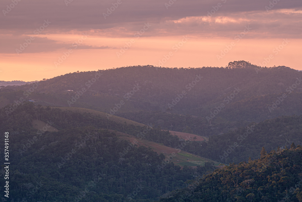Pôr-do-sol na região serrana do Estado do Espírito Santo, Brasil, mostrando vales e morros cobertos de mata.