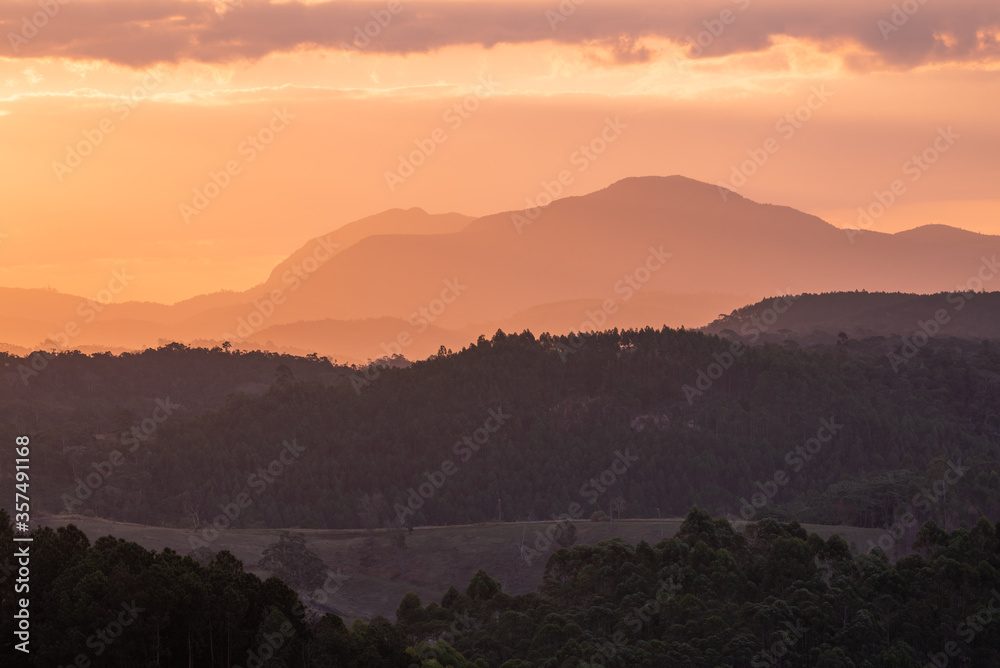 Pôr-do-sol na região serrana do Estado do Espírito Santo, Brasil, mostrando vales e morros cobertos de mata.