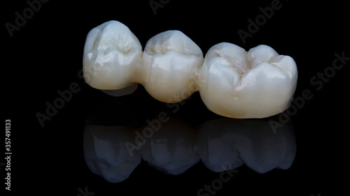 zirconium dental crowns on black glass with reflection