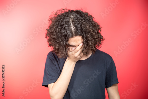 Portrait Of Serious Teenage Boy Standing Against Red Background © Ramil