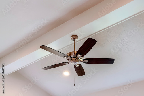 Decorative wood beam with standard ceiling fan and lights inside a house