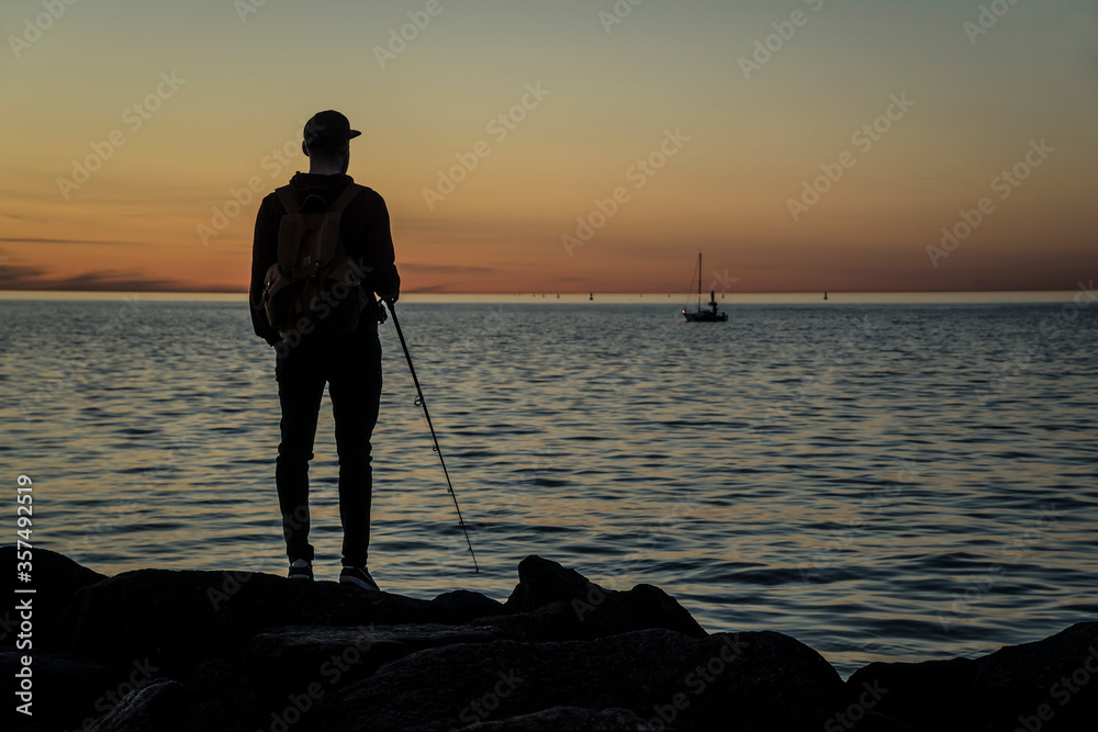 silhouette of a man on the beach fishing