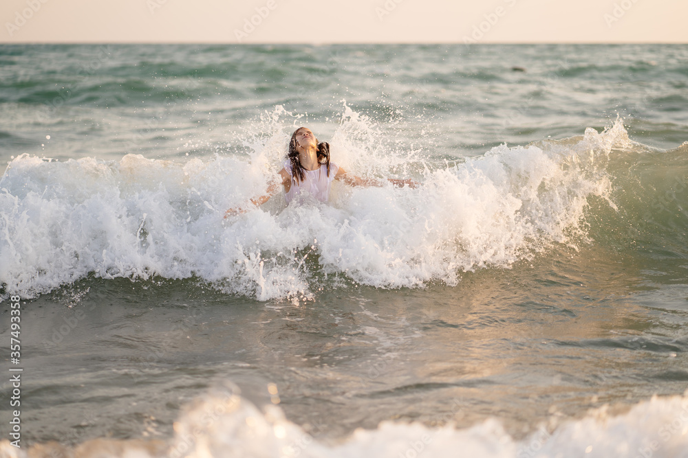 teenager girl in dress swims in sea with high waves. entertainment in vacation. teenager girl in dress swims in sea with high waves. entertainment in vacation.