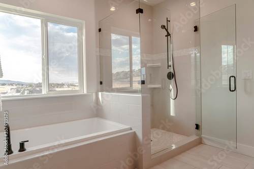 Built in bathtub with black faucet and shower stall with half glass enclosure photo