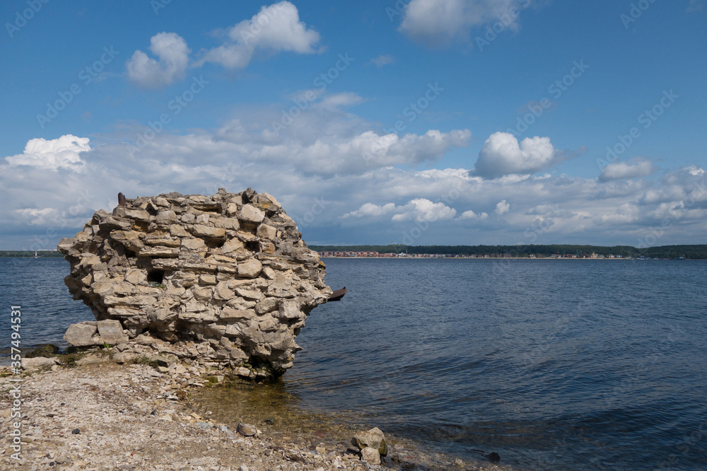 Ruins of brick smokestack of ancient Limestone factory on gravel shoreline of river Volga