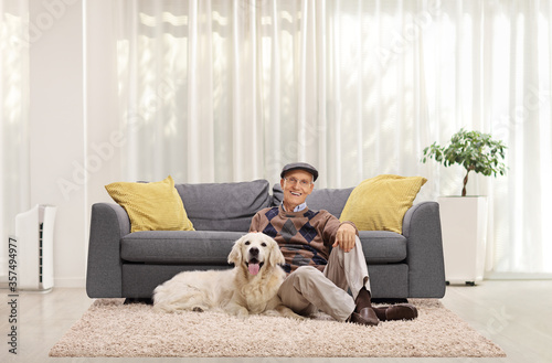 Mature man and a retriever dog sitting on the floor at home