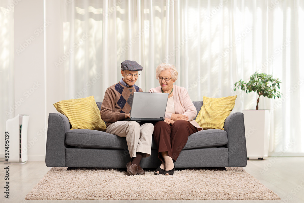 Elderly couple sitting on a sofa and using a laptop