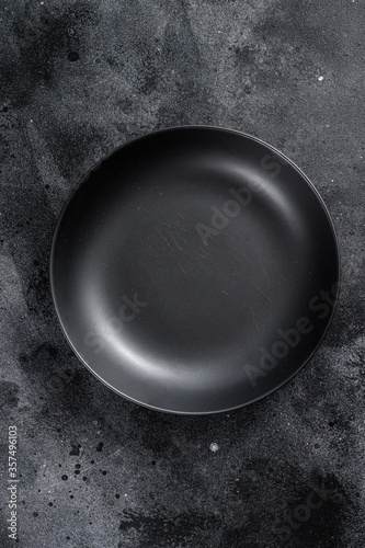 Black plate on textured black background.  Top view. Copy space