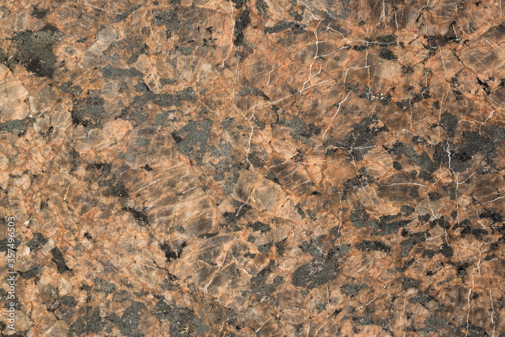 The texture of the rock. Natural stone background. Brown mineral with black spots. The texture of the rock. Natural stone background. Brown mineral with black spots.