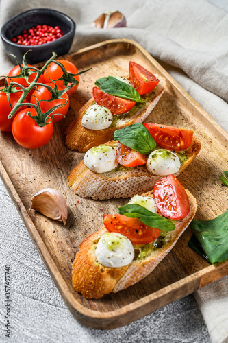 sandwiches with tomatoes, mozzarella cheese and basil. italian appetizer, antipasto. gray background. top view