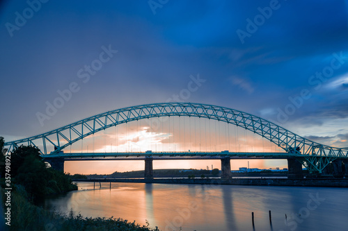Fototapeta Naklejka Na Ścianę i Meble -  Silver Jubilee Bridge in Runcorn with the sun setting in the background