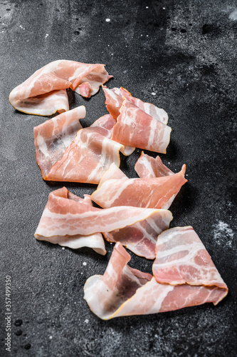 Slices of fresh pork bacon. Organic raw meat. Black background. Top view