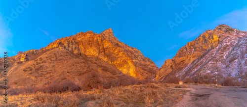 Road leading to the base of a sunlit rocky mountain in Provo Canyon Utah