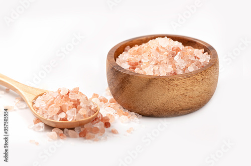 Pink salt in wooden bowl and spoon on white