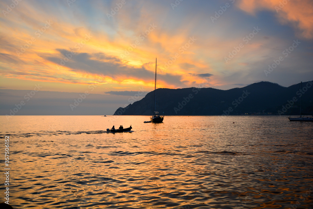 Two boats along the Ligurian coast of Vernazza harbor at sunset along the Cinque Terre, Italy
