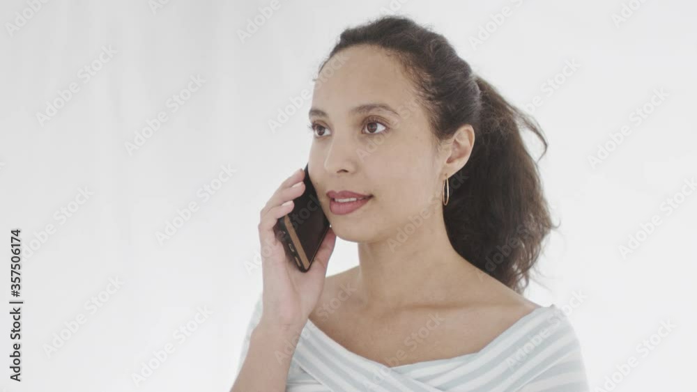 Confident young black-haired female with mobile phone by ear having telephone converdation and listening patiently. 360 degree tracking arc shot in 4K. Confident young black-haired female with mobile phone by ear having telephone converdation and listening patiently. 360 degree tracking arc shot in 4K.