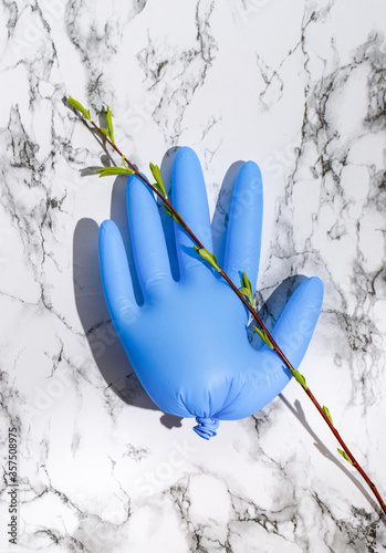 Flatlay with blue latex glove on marble background with blooming twig