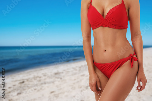 Pretty sexy woman with slim body in stylish bikini at beach on sunny day, closeup. Space for text