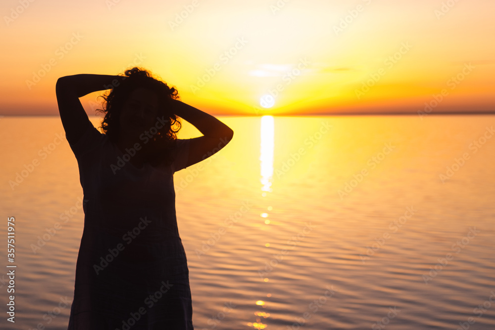 Fototapeta premium girl meets sunrise near the water