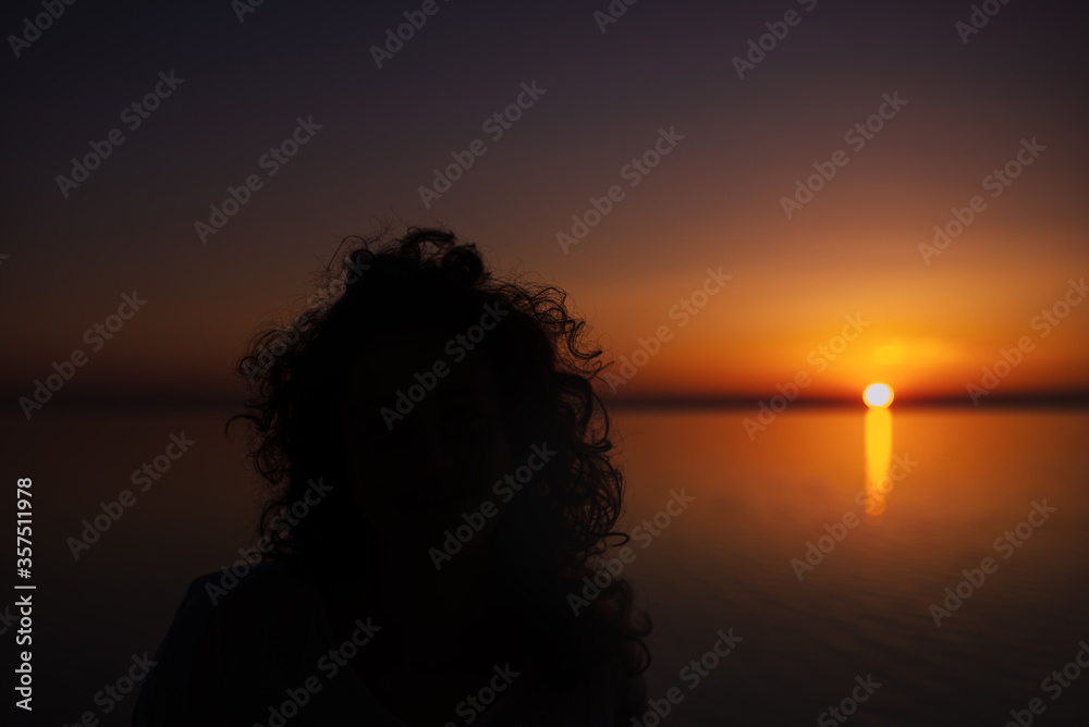 Curly girl meets sunrise over the sea