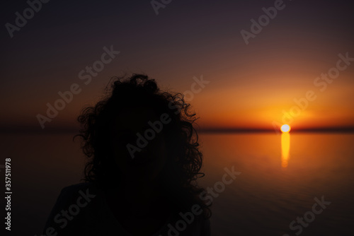 Curly girl meets sunrise over the sea