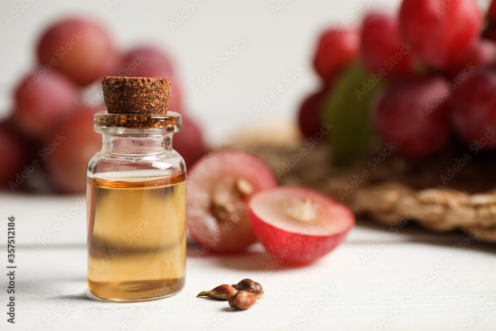 Bottle of natural grape seed oil on white wooden table, space for text. Organic cosmetic