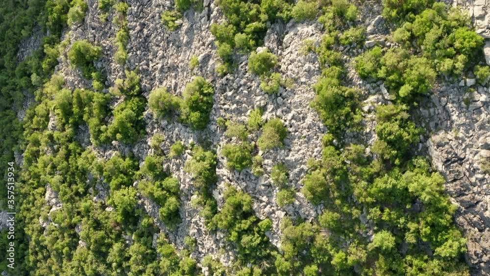 Rocky terrain with sparse green vegetation consisting of bushes, shrubs and low trees. Top aerial view on a mountain side in dry area. Rocky terrain with sparse green vegetation consisting of bushes, shrubs and low trees. Top aerial view on a mountain side in dry area.