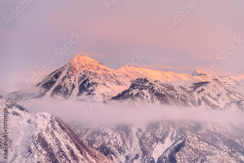 Snowy Wasatch Mountains with sharp peaks illuminated by sunset in winter