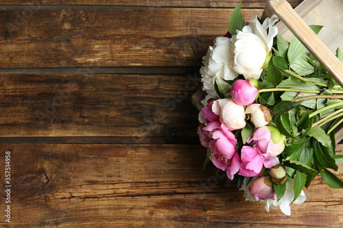Bouquet of beautiful peonies on wooden table, top view. Space for text © New Africa