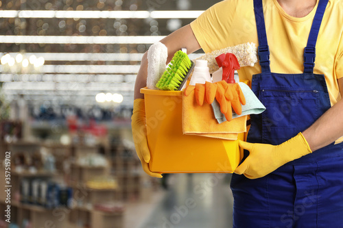 Male janitor with cleaning supplies in shopping mall, closeup. Space for text photo