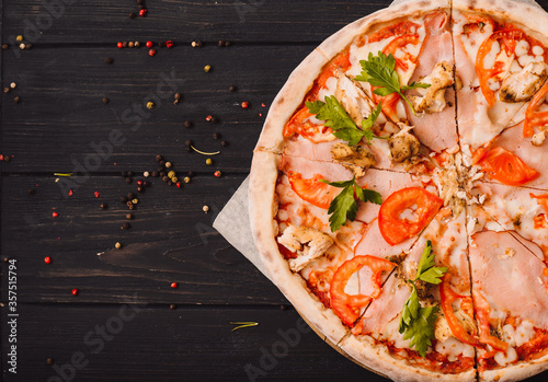 Tasty italian pizza and cooking ingredients tomatoes basil on black concrete background. Hot pepperoni pizza.