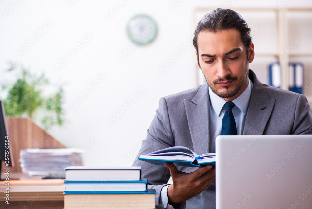 Young male businessman reading books at workplace Young male businessman reading books at workplace