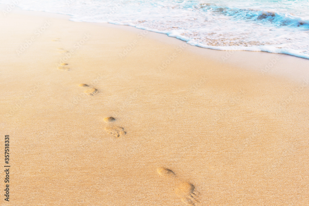 Footprints in the sand and soft sea wave on the beach background. Sunshine and copy space for text. Travel, summer holidays and vacation concept photo. Footprints in the sand and soft sea wave on the beach background. Sunshine and copy space for text. Travel, summer holidays and vacation concept photo.