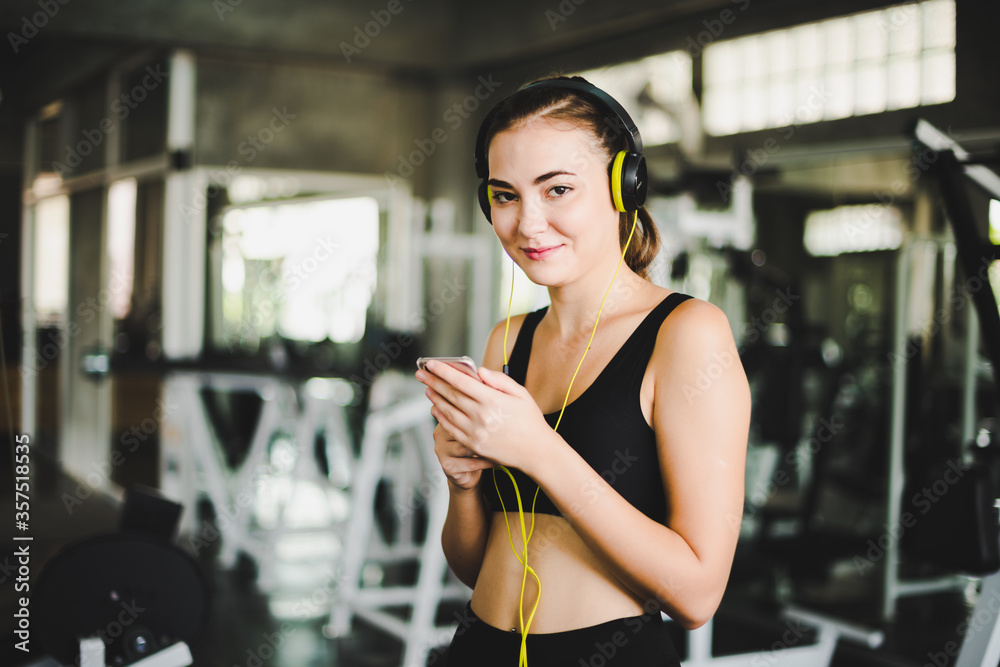 Beautiful women come to exercise in the gym and are relaxed by listening to music from headphones. She wears a sportswear. Beautiful women come to exercise in the gym and are relaxed by listening to music from headphones. She wears a sportswear.