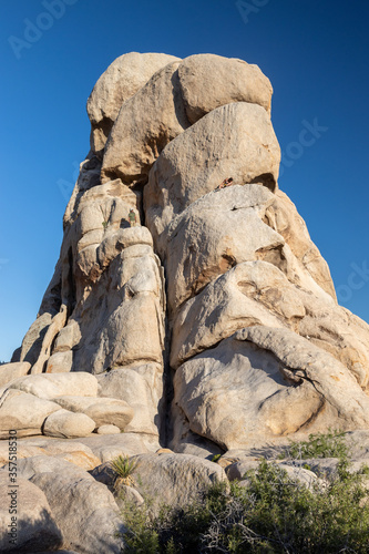 Hikers Climbing a Large Rock in the Middle of the Joshua Tree National Park Desert