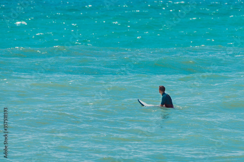 Fototapeta Naklejka Na Ścianę i Meble -  Surfer with surfboard on water. Blue sea surface background