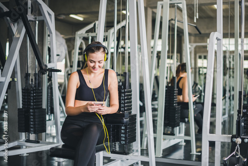 Beautiful women come to exercise in the gym and are relaxed by listening to music from headphones. She wears a sportswear.